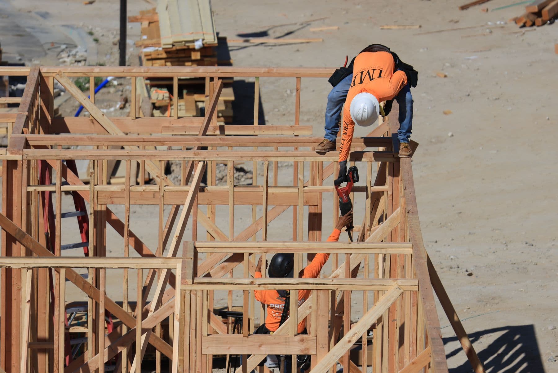 Two carpenters framing a wood house, working together as a team