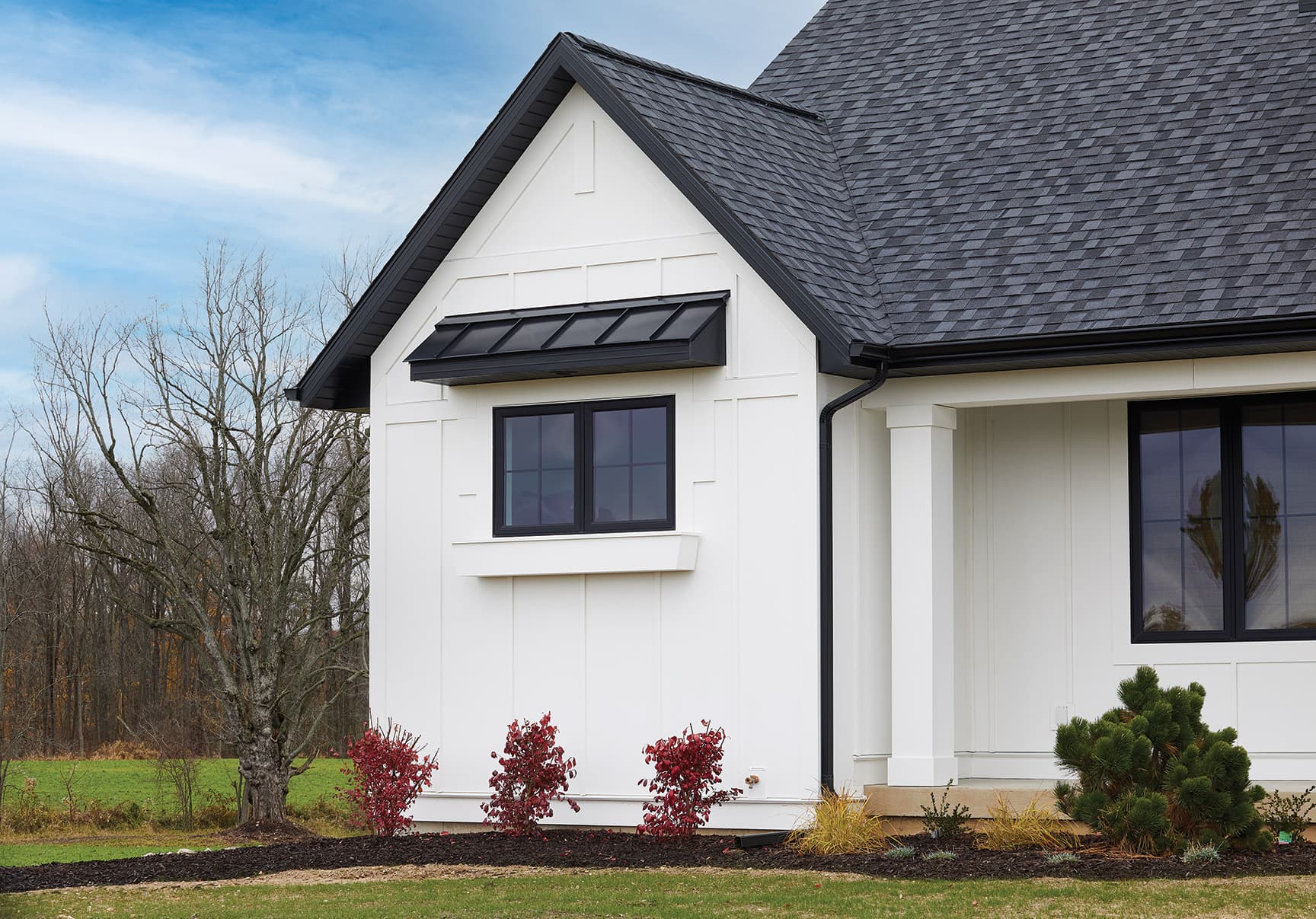 A modern farmhouse with white cellular-PVC board-and-batten siding and black windows