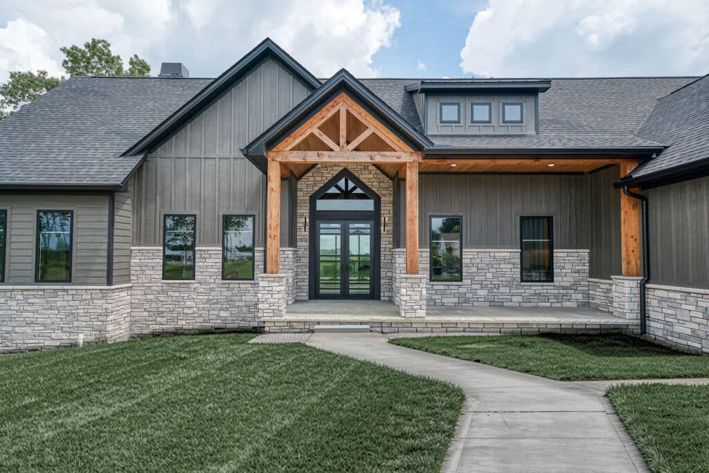 A gray board-and-batten modern farmhouse entry with stone and a timber-truss porch, in LP SmartSide