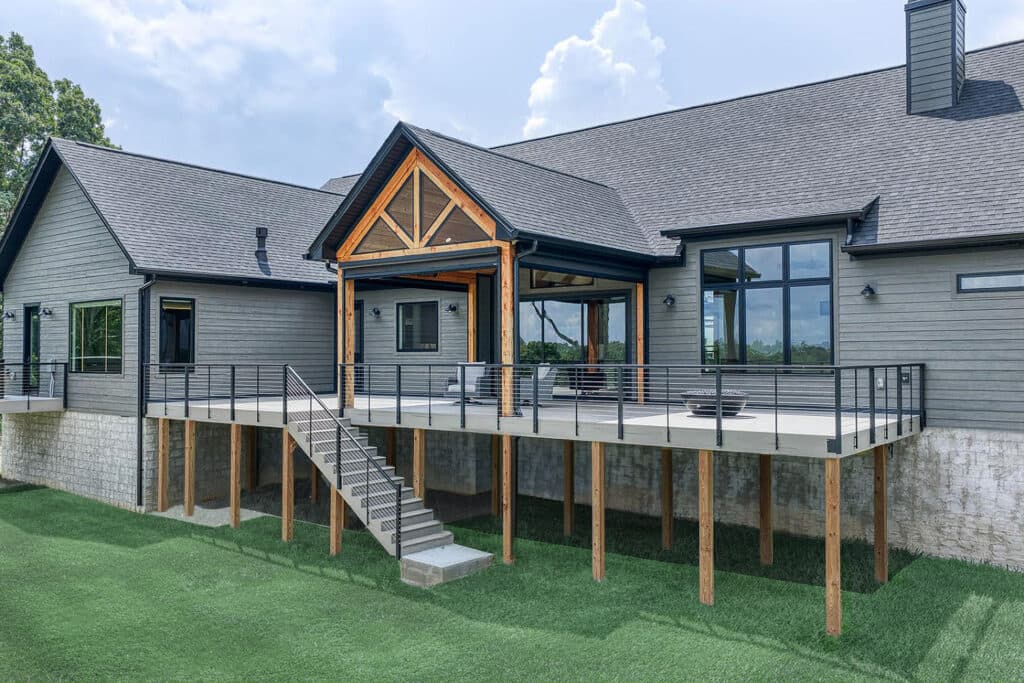 The rear of a gray modern farmhouse with an elevated deck, clad in LP SmartSide