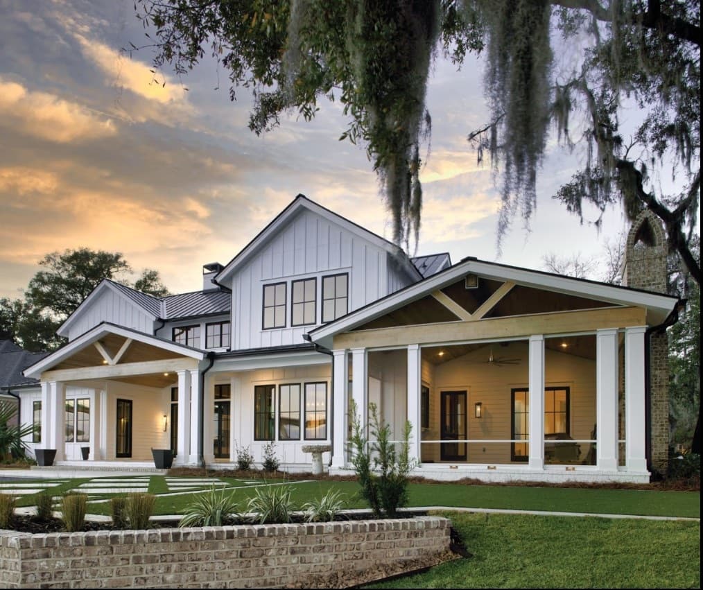 A white board-and-batten modern farmhouse with black-framed Marvin windows under a live oak