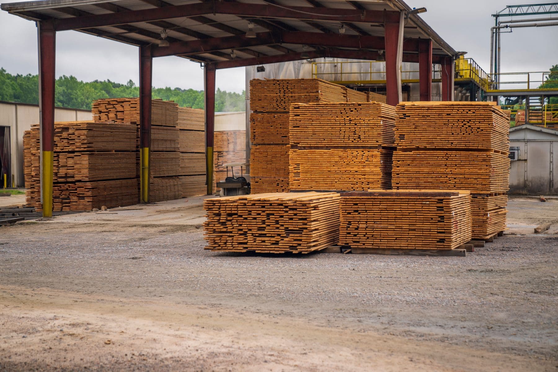 Neatly stacked dimensional framing lumber under a covered shed at a lumberyard