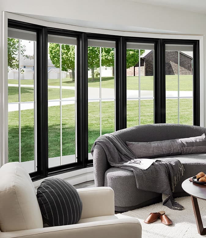 A curved bow window in a modern living room with a gray sofa