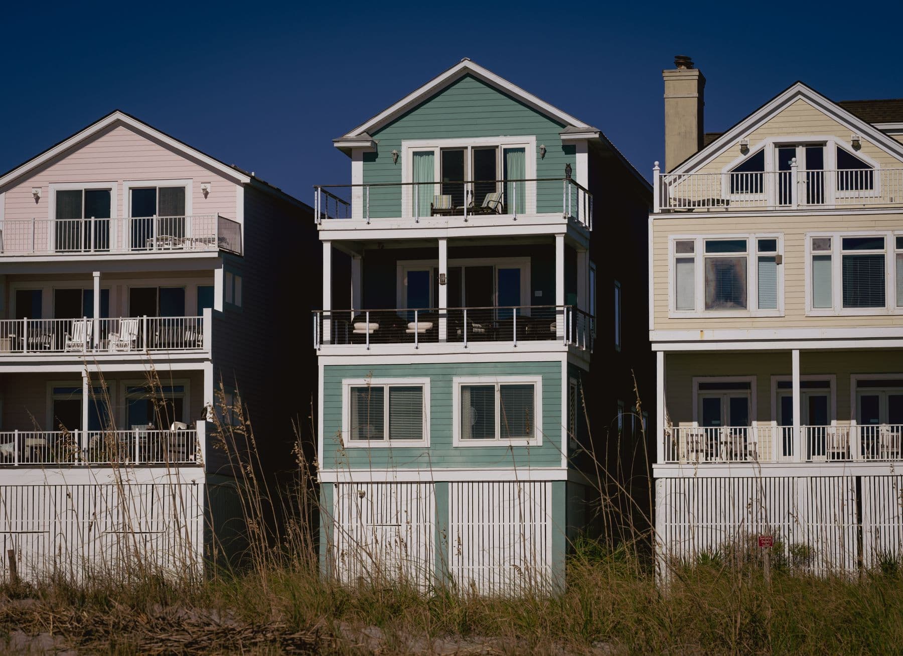 Coastal homes clad in horizontal lap siding with white trim under a deep blue sky